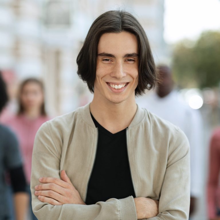 Strike, riot, protest, demonstration concept. Cheerful young man standing over multiracial crowd on street, male leader leading multiracial group of strikers chanting slogans, selective focus on man