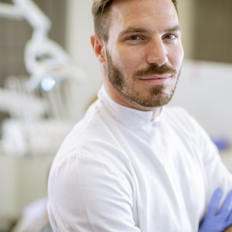Handsome dentist posing in the modern dental office