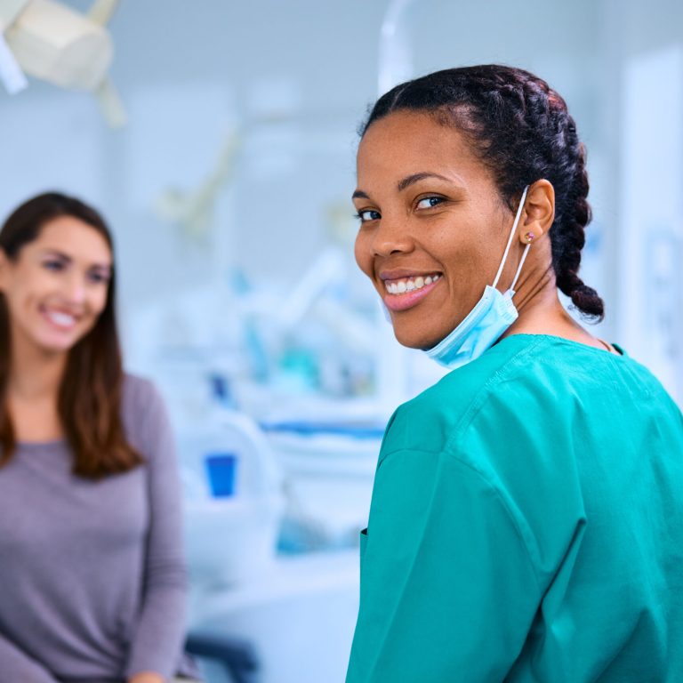 Happy African American dentist with her patient at dental clinic looking at camera.
