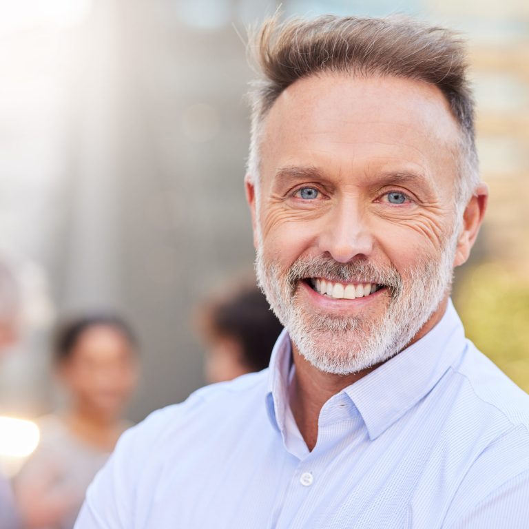 Shot of a handsome mature businessman standing outside while his colleagues stand behind him.